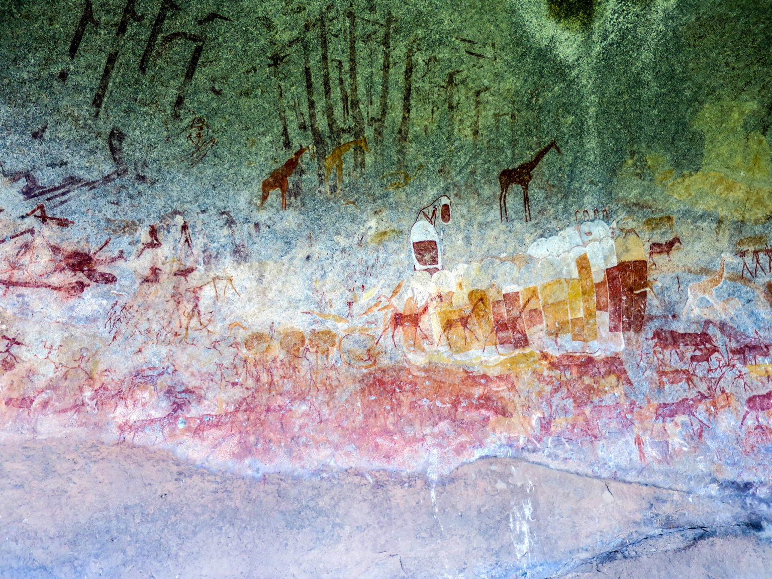 Giraffe and antelope painted in several colours across the rock at Inanke cave