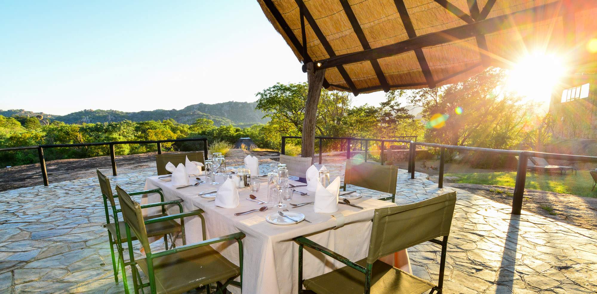 White-clothed tables on the thatched restaurant terrace in low golden light
