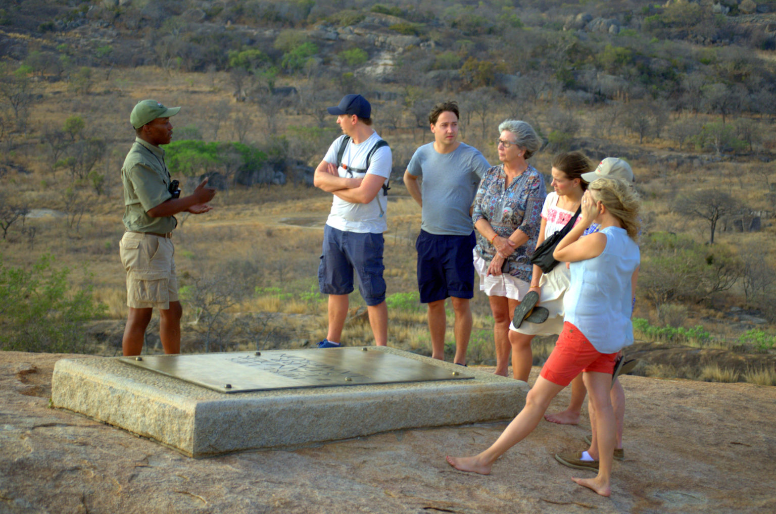 A guide talking to a group of guests beside one of the granite graves on the summit