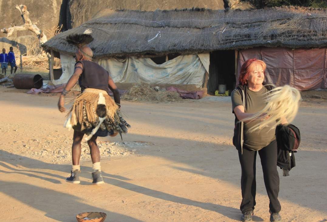 A villager in traditional dress dancing with a guest