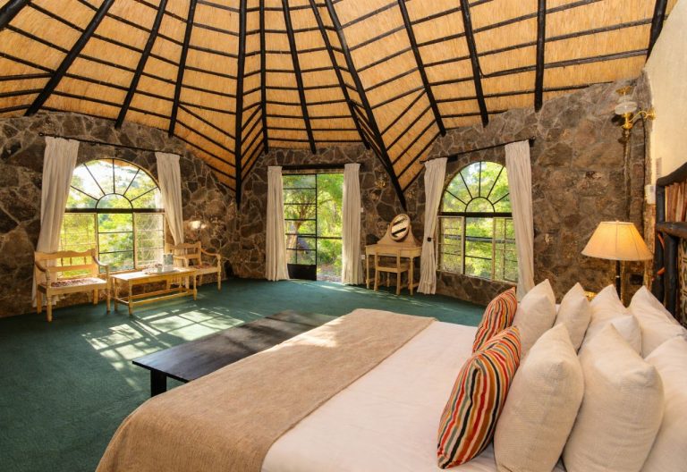 A stone chalet with a thatched roof and a double bed