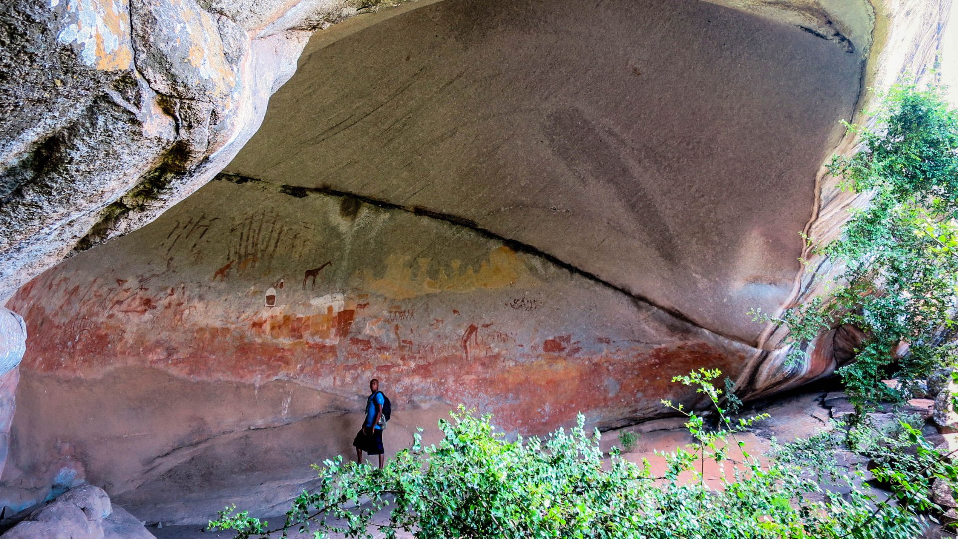 Guide illuminating ancient San rock art paintings inside a granite cave in Matobo Hills Zimbabwe