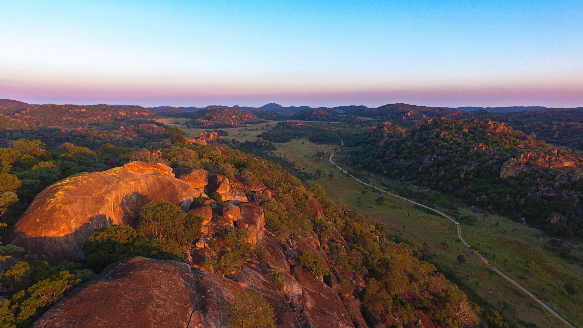 Panoramic view of Matobo Hills Zimbabwe with ancient granite kopjes against a dramatic sky at golden hour