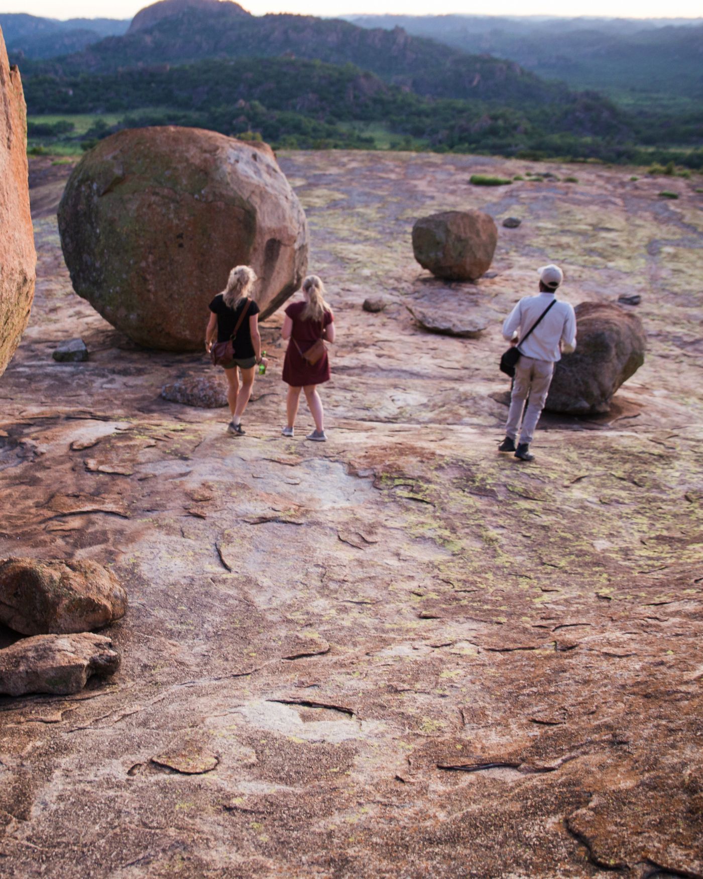 Three walkers crossing the bare granite of the dome towards the summit boulders