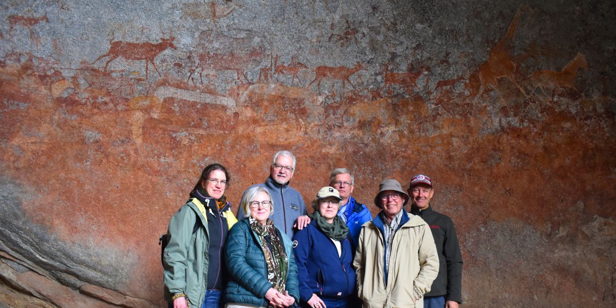 A group of guests standing in front of a painted rock wall