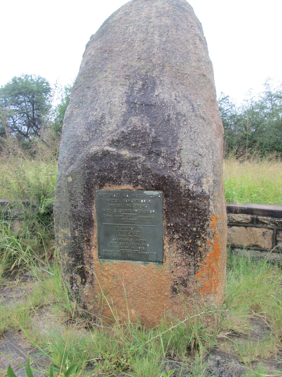 A bronze memorial plaque set into a granite boulder among grass