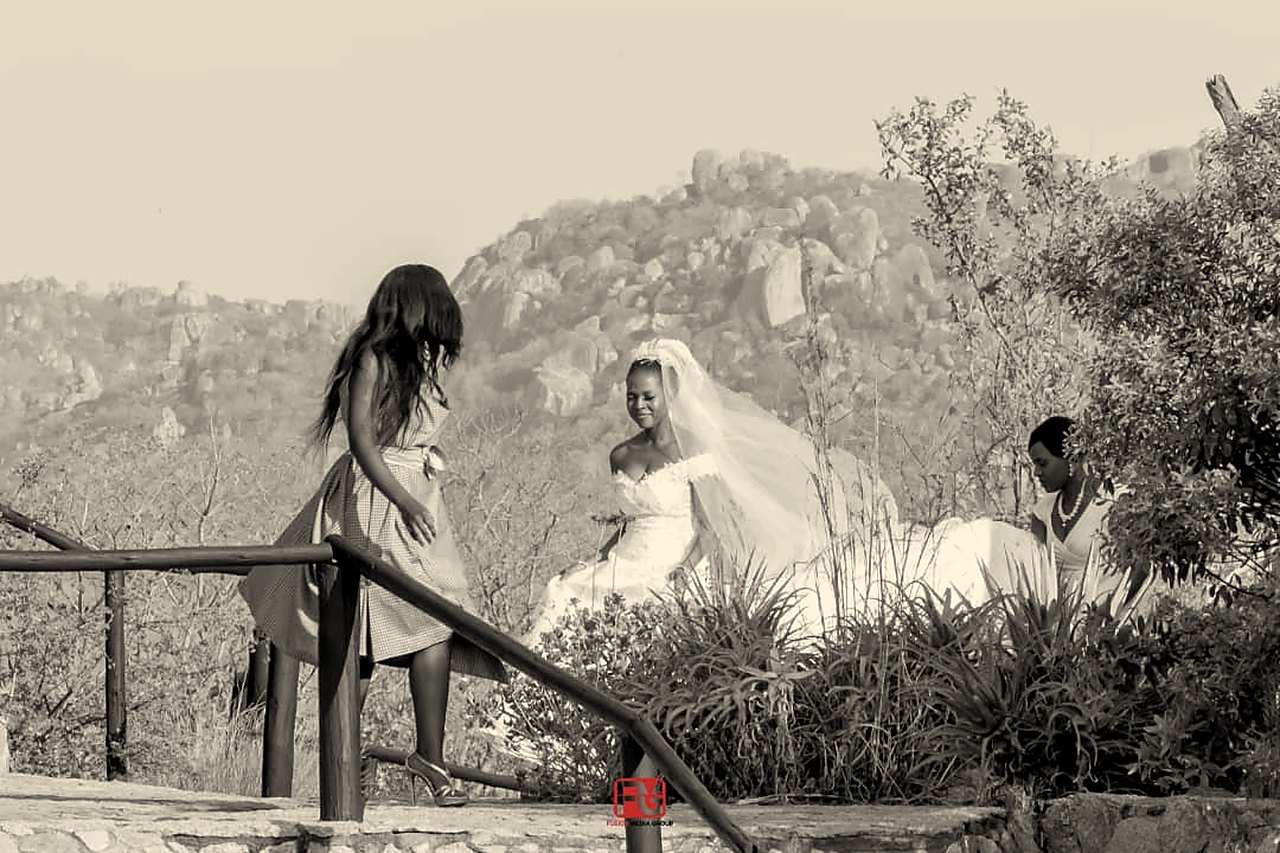 Bride walking toward an open-air ceremony on a granite deck at Matobo Hills Lodge.