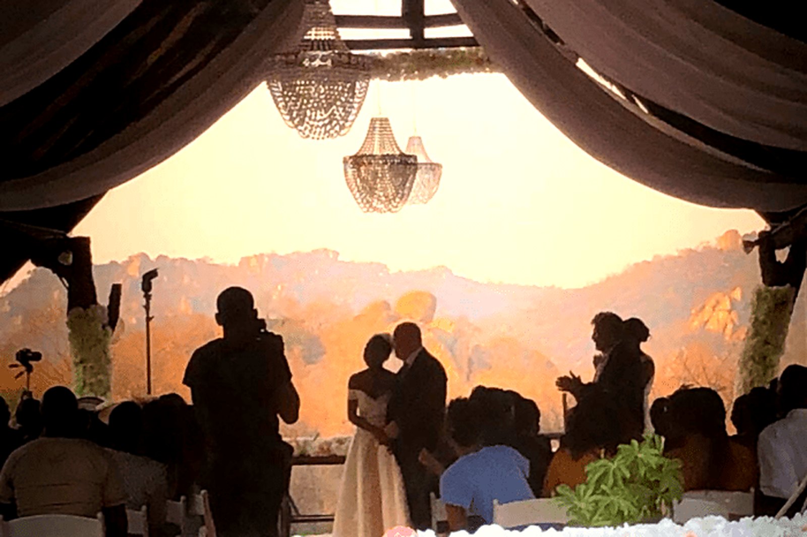 Couple exchanging vows under thatch with the Matobo Hills glowing behind them.