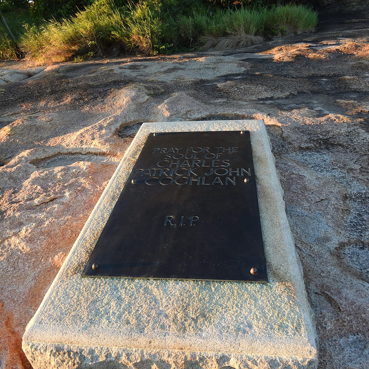 A bronze plaque for Charles Patrick John Coghlan set flat into granite on a hilltop
