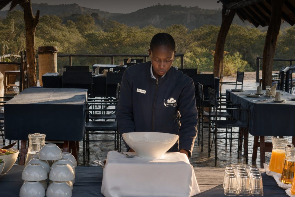 A Matobo Hills Lodge team member preparing breakfast on the open dining deck