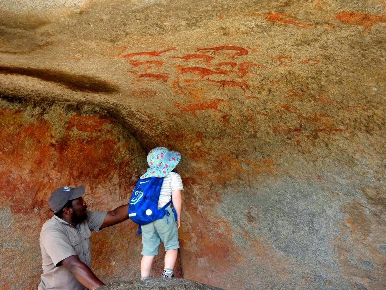 A guide and a young visitor looking at San rock paintings